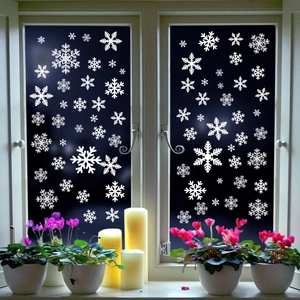 Detail of white snowflake static stickers on a window with warm festive decorations