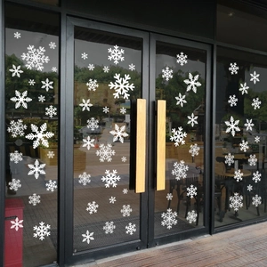 Detailed view of white Christmas snowflake static window decals on a glass door surface