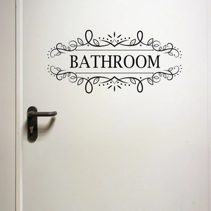 Detail of a black floral bathroom sign sticker on a white door for wall decoration