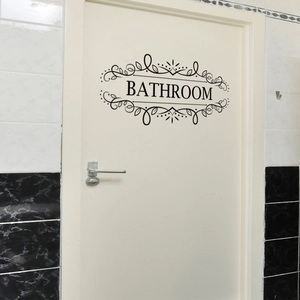 Detail of black vinyl bathroom door sticker with elegant scroll patterns on a white door
