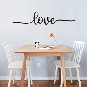 Artistic black 'love' wall decal script applied to a light blue living room wall