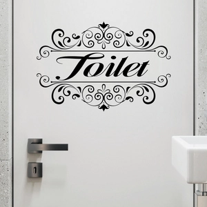 Detail of black cursive Toilet wall sticker with elegant scroll patterns on a white door