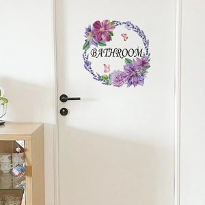 Macro detail of purple floral wreath sticker with Bathroom lettering on a white door