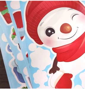 Close-up of glossy Christmas window stickers featuring cute snowmen and winter snowflakes