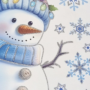 Detail of blue snowman window sticker with silver glitter finish and festive snowflake accents