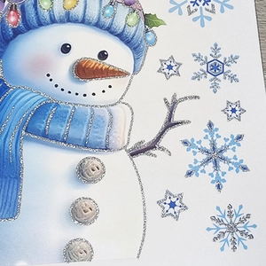 Detail of Christmas window sticker featuring a snowman with blue hat and silver glitter edges