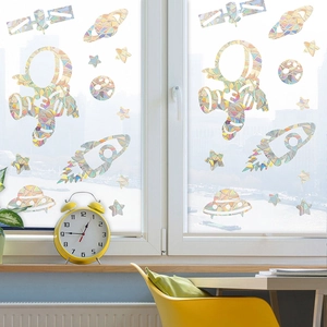 Detailed astronaut and rocket prism window stickers reflecting rainbow light on glass