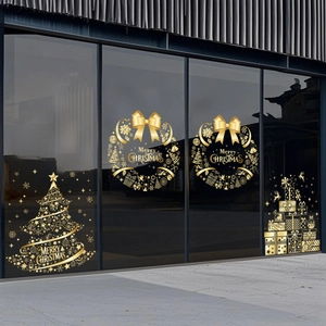 Close-up of golden Merry Christmas window decals with wreaths and tree on glass