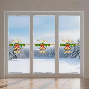 Detail of Merry Christmas 2025 window stickers with gold bells and red bows on glass