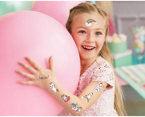 Colorful cartoon unicorn and rainbow temporary tattoos applied on a child for party fun