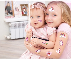 Close-up of children wearing cute waterproof unicorn and rainbow temporary tattoos on faces