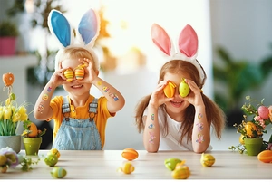 Close-up of children showing colorful Easter bunny and egg temporary tattoos on arms