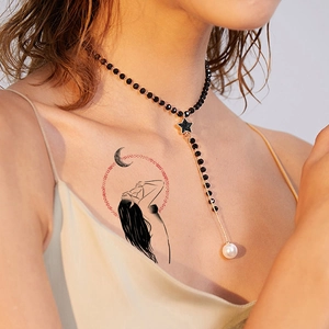 Minimalist temporary tattoo of a girl under the moon applied on chest skin area