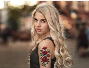 Detail of vintage red peony temporary tattoo sticker on woman's upper arm outdoors