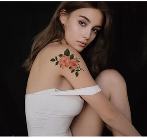 Détail macro d'un tatouage éphémère floral avec fleurs roses sur l'épaule