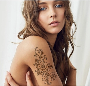 Close-up of black mandala flower temporary tattoo on arm with delicate floral line art