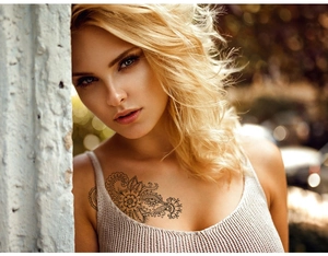Detail of waterproof mandala flower temporary tattoo applied on woman's collarbone