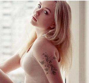 Detail of a black mandala flower temporary tattoo sticker on a woman's upper arm