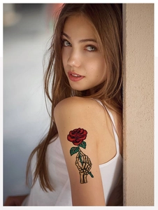 Detail eines temporären Tattoos mit Rose und Skeletthand auf dem Arm einer Frau mit Schattierung