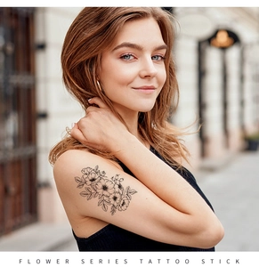 Detail of floral sketch tattoo sticker showing black ink flower design on female arm