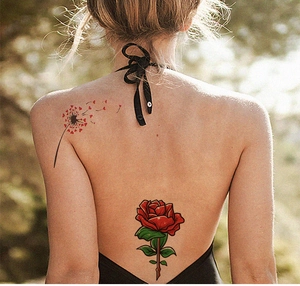 Detail von wasserdichten Rosen- und Löwenzahn-Tattoos auf dem Rücken einer Frau