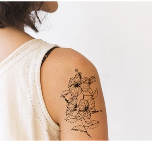 Detail of floral sketch tattoo sticker with black line hibiscus flowers on a woman's shoulder