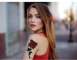 Detailansicht eines realistischen Rosen-Tattoos mit roten Blüten auf dem Frauenarm