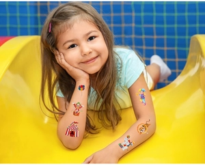 Girl showing circus-themed temporary tattoos with colorful clowns and tents on arm