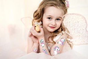 Girl wearing colorful unicorn temporary tattoos with dreamlike fairy wings decoration