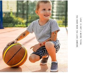 Close-up of vibrant basketball theme temporary tattoo stickers on child's arm outdoors