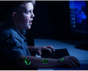 Tatouages temporaires dinosaures fluorescents sur le bras d'un enfant dans le noir