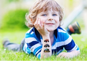 Detail of colorful monster truck temporary tattoos on a child's arm in a park setting