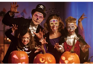 Family wearing Day of the Dead floral face tattoos with glowing Halloween pumpkins behind
