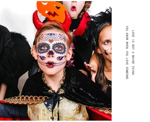 Detail of glow-in-the-dark Halloween face tattoos with spider web and floral patterns on a boy