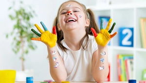 Girl showing colorful unicorn glitter tattoo stickers on face and arms for kids party