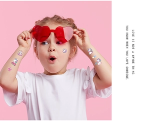 Girl wearing unicorn glitter temporary tattoo stickers with pink heart glasses
