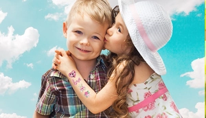 Close-up of glittery heart and love tattoo stickers on a child hand under sunny sky