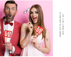 Detailed view of colorful glitter Valentine hearts and butterfly temporary tattoos on arms