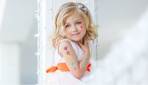 Details von Glitzer-Meerjungfrau-Tattoos mit bunten Herzen auf Kinderarm und Gesicht