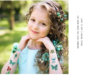 Close-up of glitter butterfly and colorful dreamcatcher temporary tattoos on a child's arm