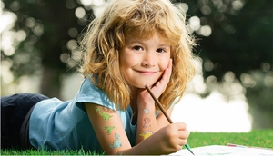Close-up of colorful glitter dinosaur temporary tattoos on a child's hand outdoors