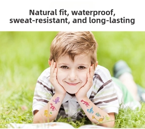 Boy on green grass showing colorful waterproof cartoon dinosaur temporary tattoos on his arms