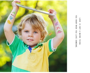 Close-up of colorful glitter dinosaur temporary tattoos applied on a child's arm outdoors
