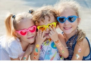 Children wearing colorful waterproof cartoon tattoos on arms in outdoor sunny party setting