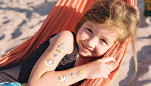 Girl wearing shiny laser gold unicorn temporary tattoos at a beach setting for kids