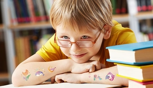 Boy showcasing colorful space and marine cartoon temporary tattoos on his arm