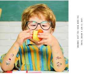 Child wearing laser gold cartoon space tattoos with owls and stars on the arm