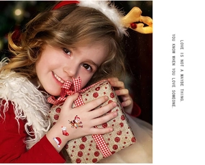 Close-up of child holding gift box featuring festive Christmas cartoon temporary tattoos