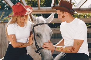 Close-up of cowboy themed temporary tattoos with sheriff stars and cacti on a model's skin