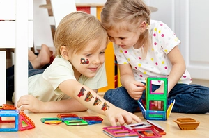 Children at home showing colorful cartoon train temporary tattoos on face and arm